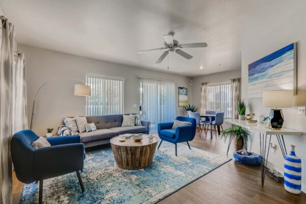 Pavilions at Arrowhead apartment living room with colorful chairs, plush couch, large artwork, and balcony door.