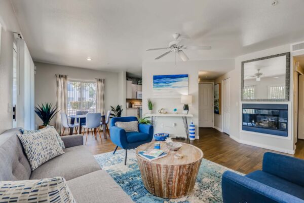 Pavilions at Arrowhead apartment living room with colorful rug, plush seating, fireplace, and large mirror.