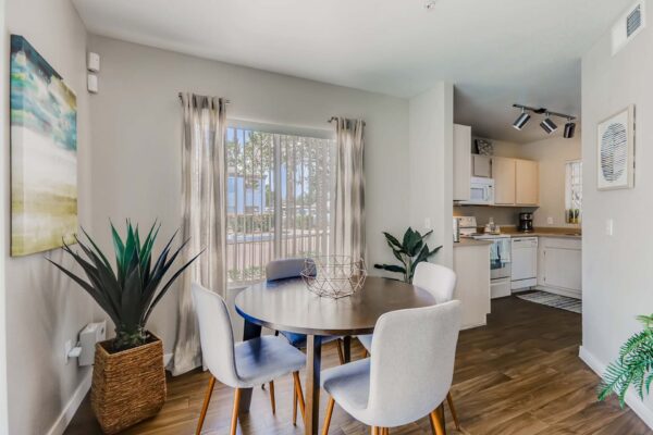 Pavilions at Arrowhead apartment dining room with wood style floor, round table with chairs, and large window.