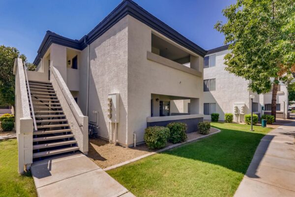 Pavilions at Arrowhead apartments with simple architecture, lush lawns, and tall trees.