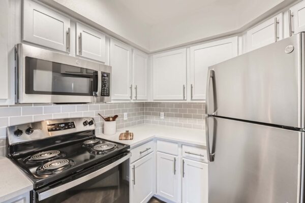 Pavilions at Arrowhead apartment kitchen with white cabinets and counters and stainless steel appliances.