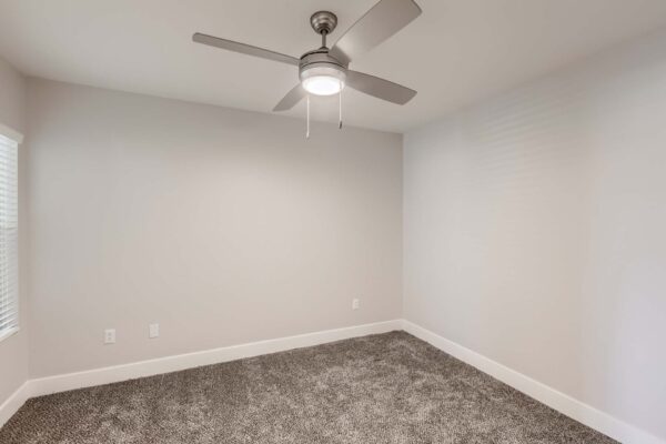 Pavilions at Arrowhead apartment bedroom with plush carpet and ceiling fan.