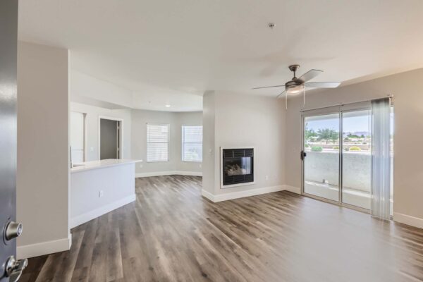 Pavilions at Arrowhead apartment living area with wood style floor, ceiling fan, and fire place.