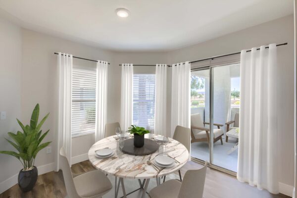 Pavilions at Arrowhead apartment dining room with round dining table, balcony door, and large windows.