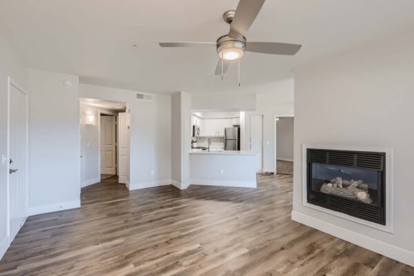 Pavilions at Arrowhead apartment living room with wood style floor, fireplace, and ceiling fan.