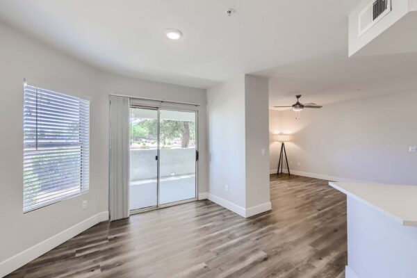 Pavilions at Arrowhead apartment living area with wood style floor, ceiling fan, and balcony doors.