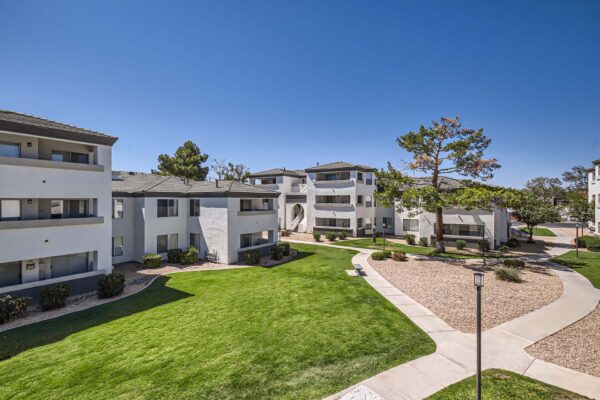 Pavilions at Arrowhead apartments with lush rocky landscaping and tall trees.