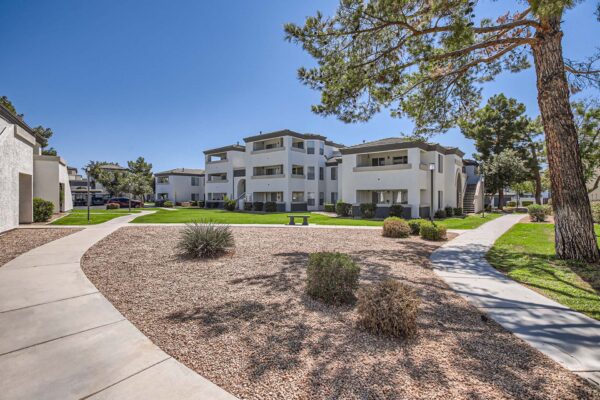 Pavilions at Arrowhead apartments with lush rocky landscaping and tall trees.