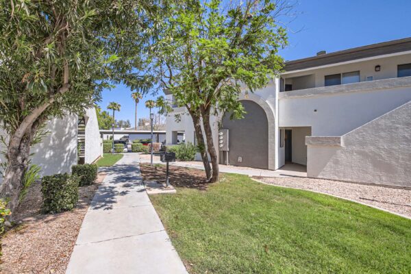Pavilions at Arrowhead apartments with lush rocky landscaping and tall trees.
