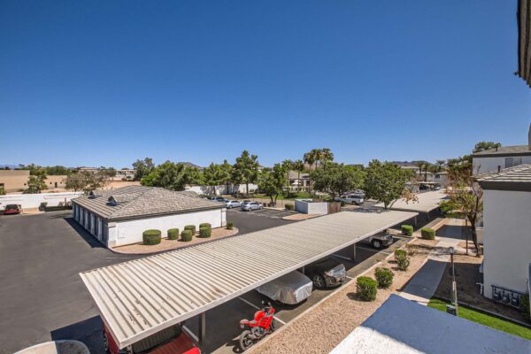 Pavilions at Arrowhead apartments with ample covered parking and lush trees.