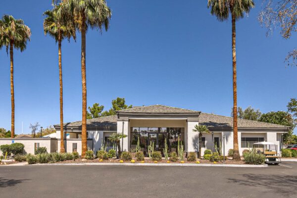 Pavilions at Arrowhead apartments clubhouse with lush cactus landscaping and tall palm trees.
