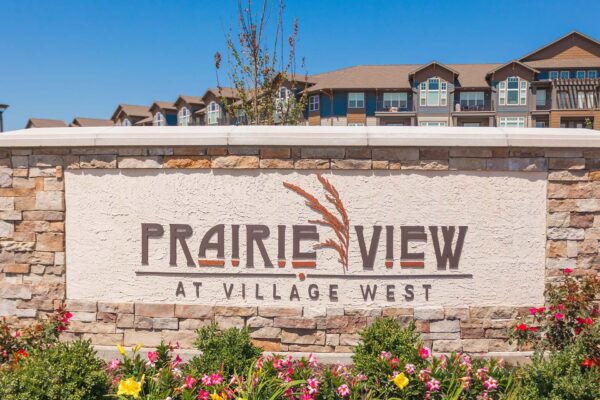 Prairie View at Village West apartments monument signage with lush flowers.