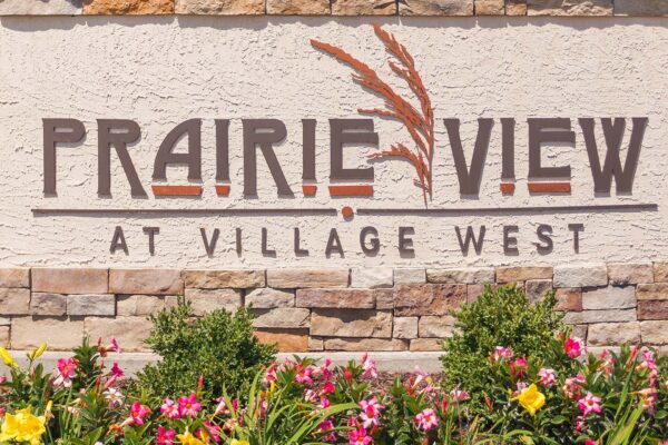 Prairie View at Village West apartments monument sign with lush flowers.