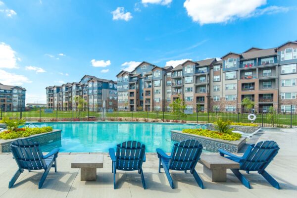 Prairie View at Village West apartments pool area with Adirondack chairs and lush planters.
