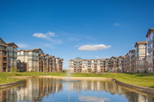 Prairie View at Village West apartments courtyard with lush green lawns and pond with fountain.