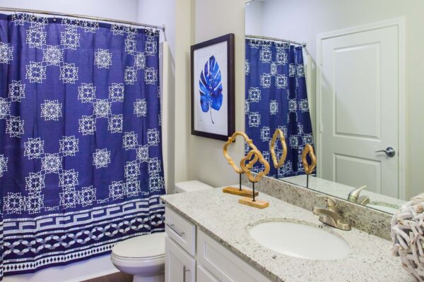 Prairie View at Village West apartment bathroom with white cabinets, light counters, and large mirror.