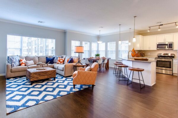 Prairie View at Village West apartment living room with wood style floor, plush sectional, and dining table.
