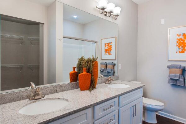 Prairie View at Village West apartment bathroom with white cabinets, light counters, and large mirror.