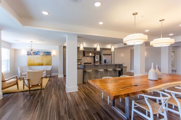 Prairie View at Village West apartments community kitchen with plush arm chairs, live edge wood dining table, and bar.