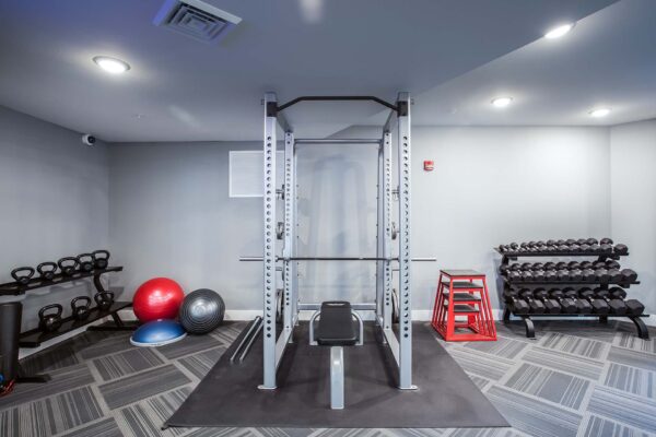Prairie View at Village West apartments fitness center with weight lifting cage and dumbbell racks.