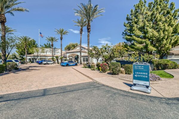 Springs at Alta Mesa apartments entrance with ample parking and lush green landscaping.