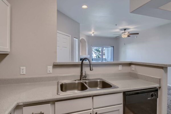 Springs at Alta Mesa apartment kitchen with white cabinets, gray counters, and stainless steel sink.