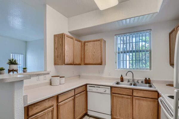 Springs at Alta Mesa apartment kitchen with wood cabinets, light counters, and white appliances.