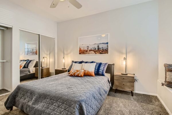 Springs at Alta Mesa apartment bedroom with carpet, plush bed with headboard, and mirrored closet doors.
