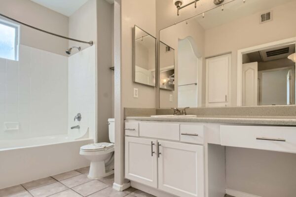 Springs at Alta Mesa apartment bathroom with tile floor, white cabinets, large mirror, and tiled shower tub.
