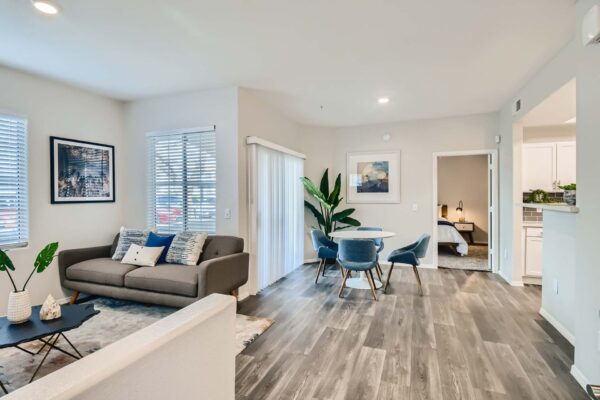 Springs at Alta Mesa apartment living room with wood style floor, plush modern seating, and dining table.