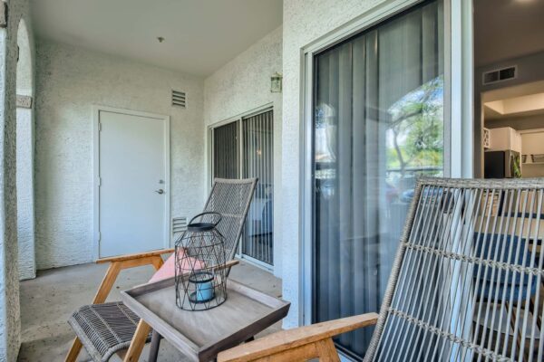 Springs at Alta Mesa apartment balcony with outdoor seating and glass door.