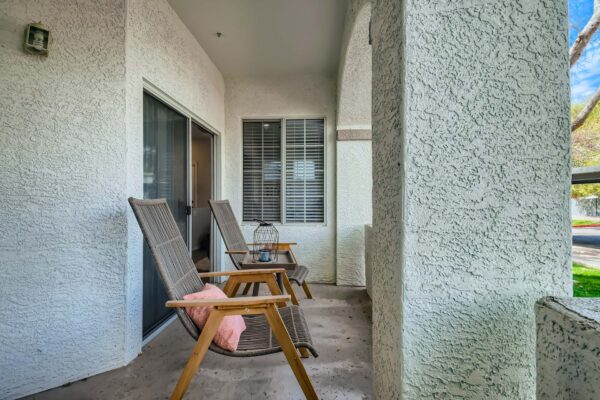 Springs at Alta Mesa apartment balcony with outdoor seating and textured walls.