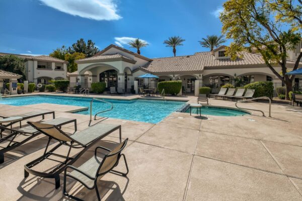 Springs at Alta Mesa apartment pool area with lounge chairs and tables with umbrellas.