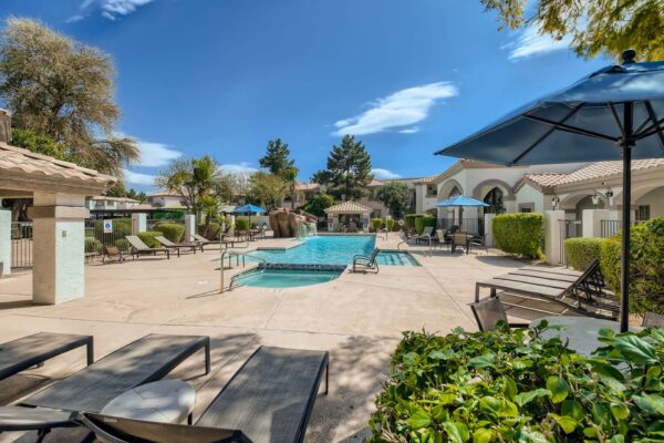 Springs at Alta Mesa apartments pool area with lounge chairs and tables with umbrellas.