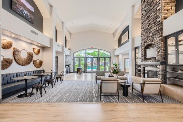 Springs at Alta Mesa apartments lobby with modern arm chairs, bench booths with tables, and fireplace with TV.