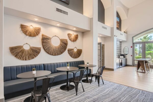 Springs at Alta Mesa apartments lobby with plush bench seats, round tables, metal chairs, and wall decor.