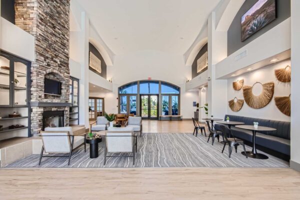 Springs at Alta Mesa apartments lobby with modern arm chairs, stone fireplace, and airy vaulted ceilings.