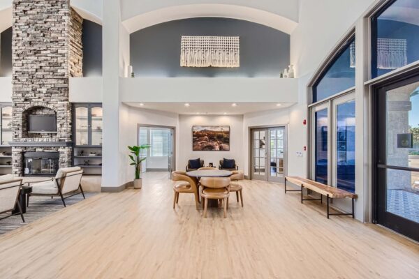 Springs at Alta Mesa apartments lobby with wood bench, round table with chairs, and airy vaulted ceilings.