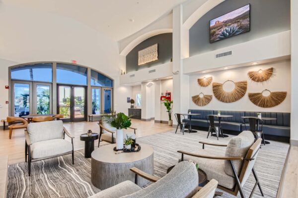 Springs at Alta Mesa apartments lobby with modern arm chairs, round coffee table with decor, and airy vaulted ceilings.
