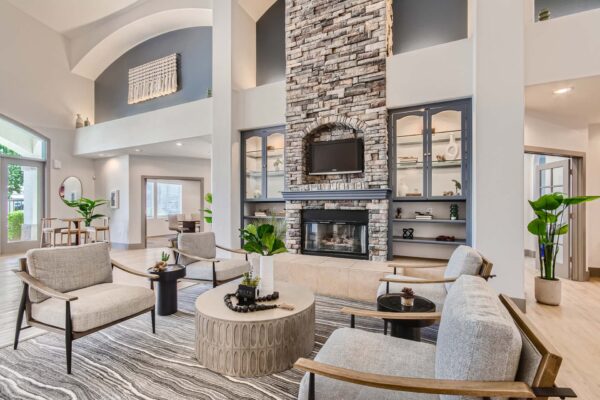 Springs at Alta Mesa apartments lobby with modern arm chairs, stone fireplace, and shelves with decor.