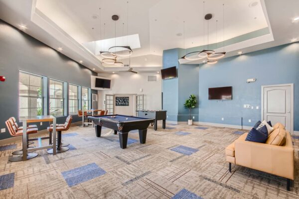 Springs at Alta Mesa apartments clubhouse with leather couch, pool table, foosball, TVs, and vaulted ceilings.