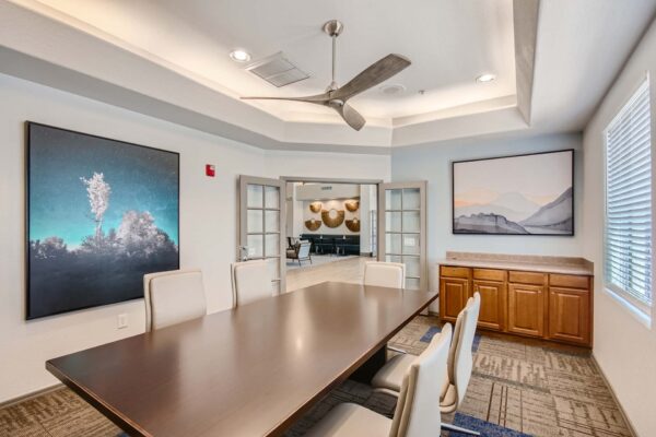 Springs at Alta Mesa apartments office with conference table, large fan, and artwork.