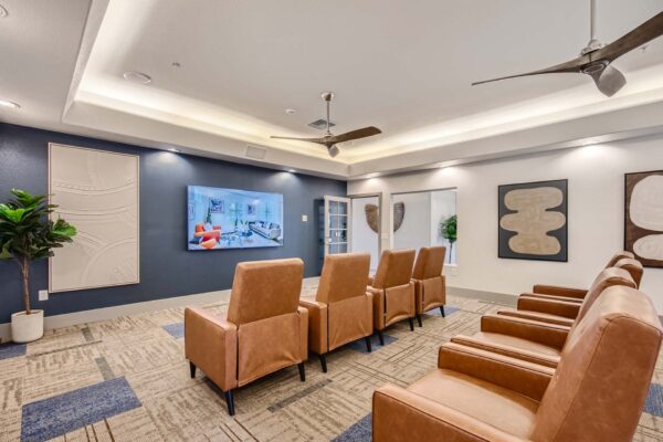 Springs at Alta Mesa apartments TV room with leather arm chairs and large TV.