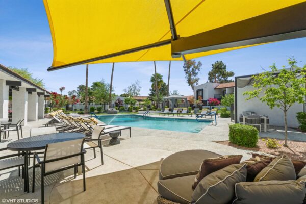 Tempe Vista apartments pool area with lounge chairs, dining table, and day bed.