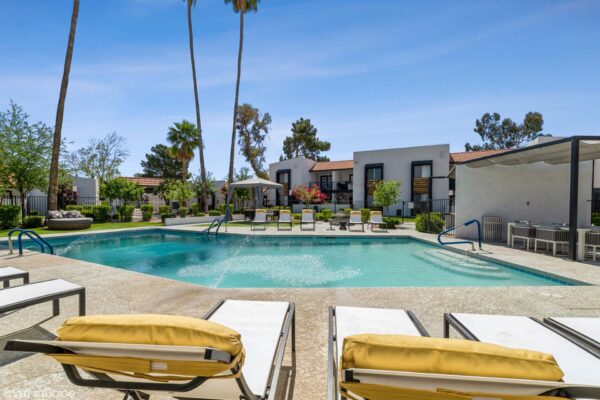 Tempe Vista apartments pool area with lounge chairs and tall palm trees.