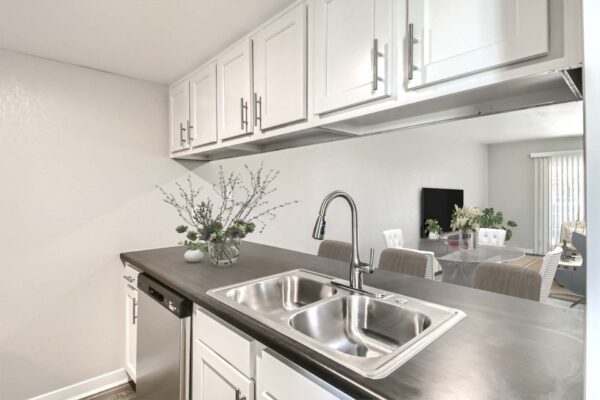 Tempe Vista apartment kitchen with white cabinets, dark counters, and stainless steel sink.