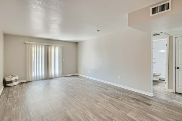 Tempe Vista apartment living area with wood style floors and balcony door.