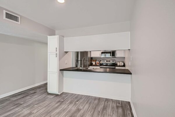 Tempe Vista apartment living area with wood style floor and modern kitchen.