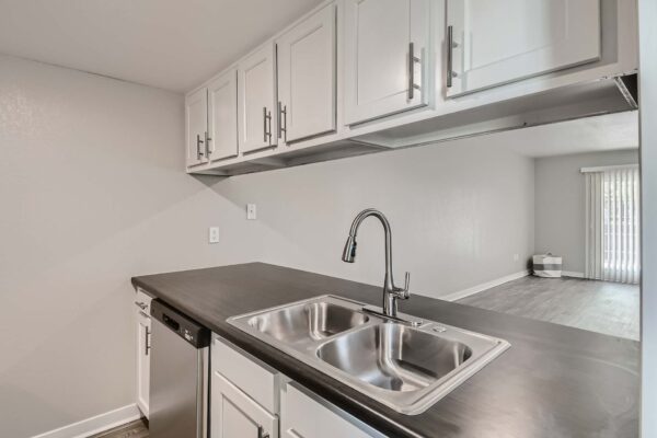 Tempe Vista apartment kitchen with white cabinets, dark counters, and stainless steel sink.
