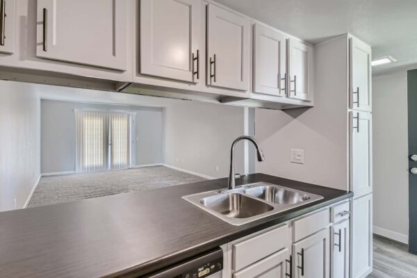 Tempe Vista apartment kitchen with white cabinets, dark counters, and stainless steel sink.
